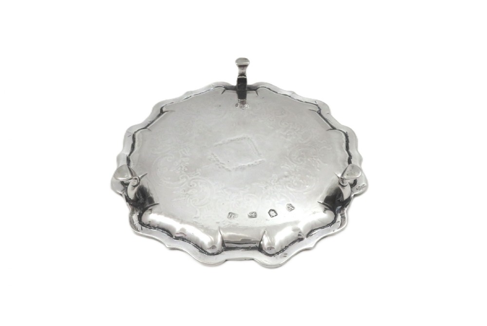 A circular 18th-century sterling silver card tray with a shaped piecrust rim, detailed scroll engraving, and a central heraldic crest. View VI