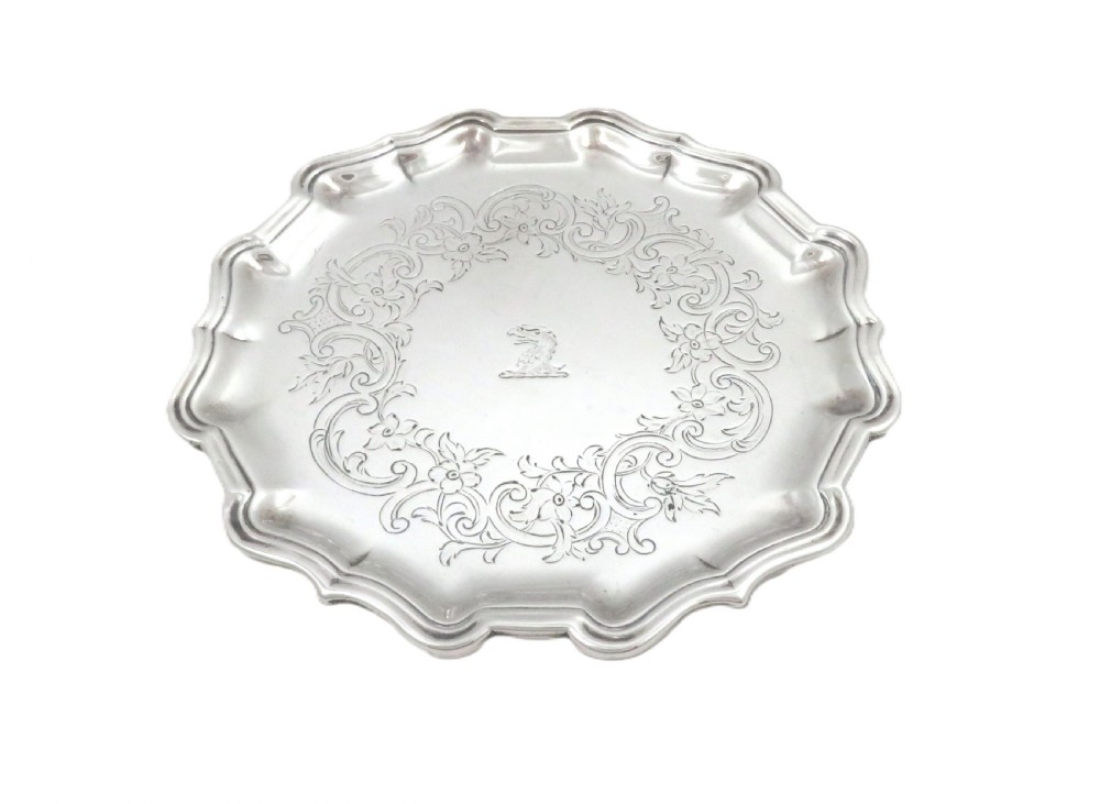 A circular 18th-century sterling silver card tray with a shaped piecrust rim, detailed scroll engraving, and a central heraldic crest. View VII
