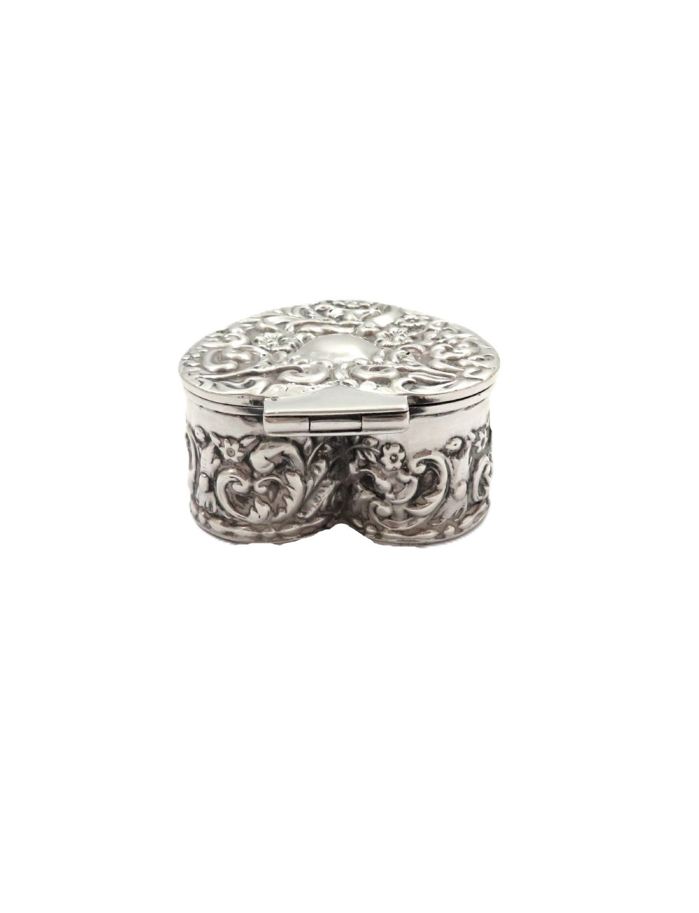 A small heart-shaped Edwardian sterling silver trinket box featuring detailed floral repousse scrolling across the lid and sides. View V