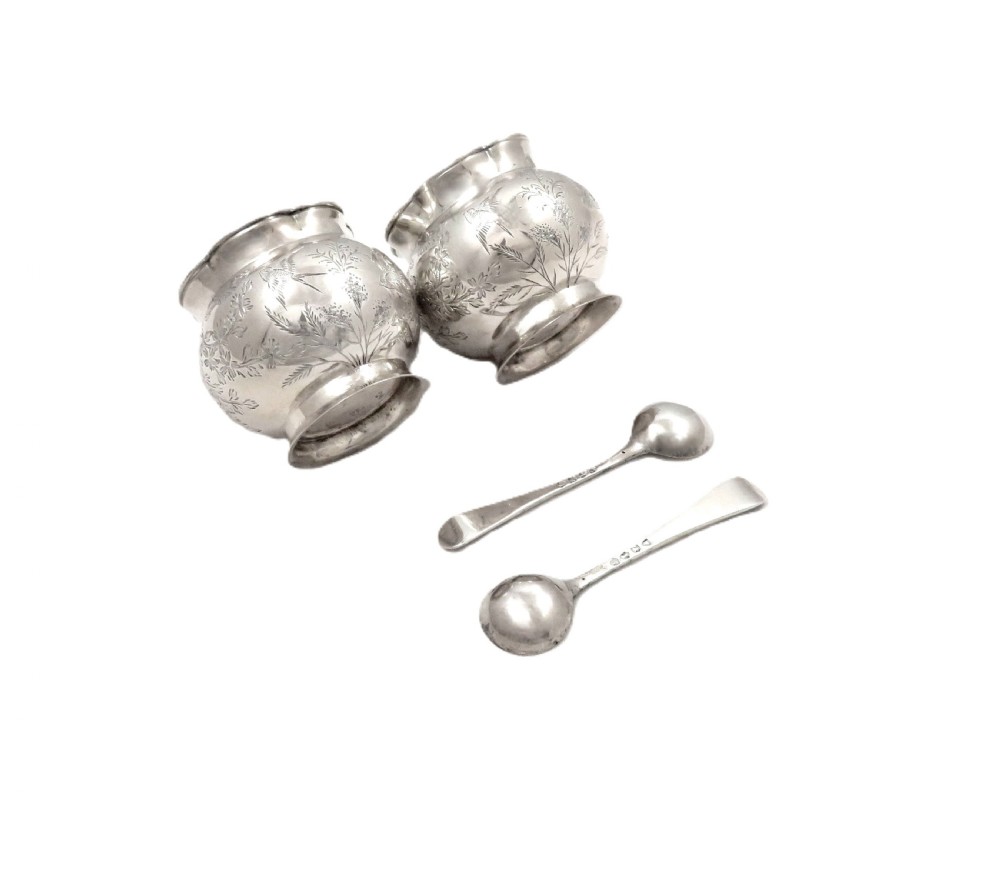 A pair of Victorian engraved sterling silver salt cellars with matching spoons displayed inside an open fitted purple silk-lined presentation case. View IV