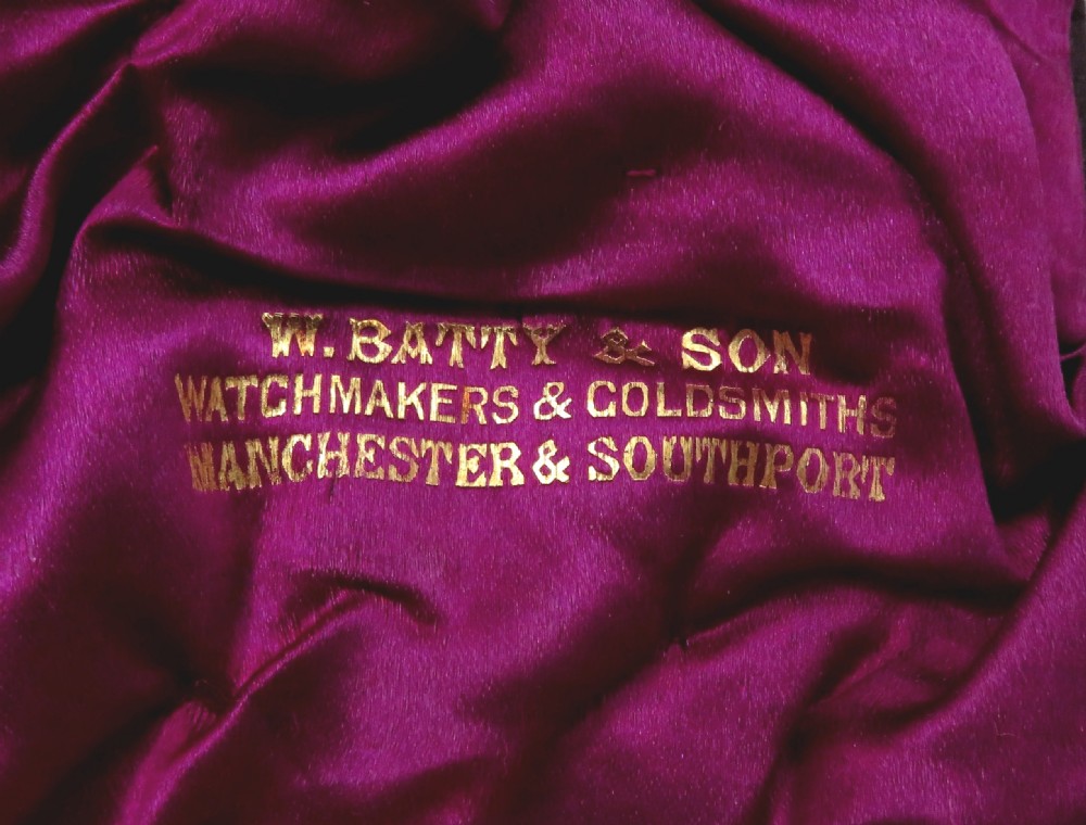 A pair of Victorian engraved sterling silver salt cellars with matching spoons displayed inside an open fitted purple silk-lined presentation case. View V