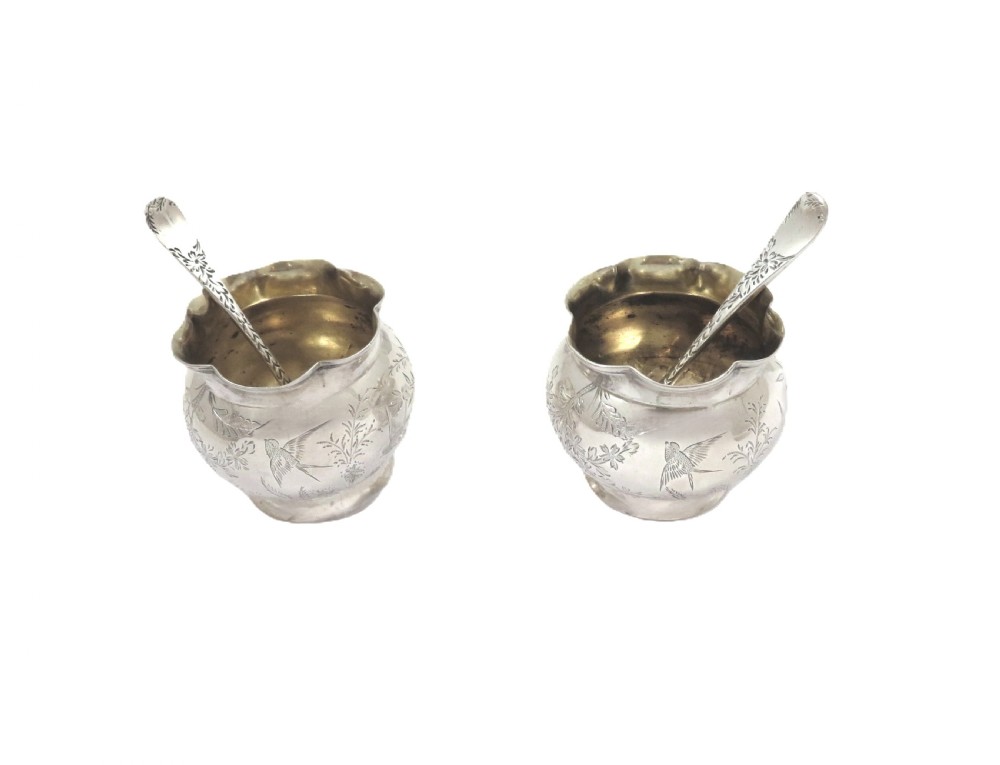 A pair of Victorian engraved sterling silver salt cellars with matching spoons displayed inside an open fitted purple silk-lined presentation case. View VI