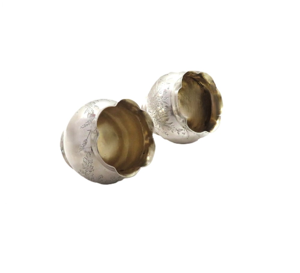 A pair of Victorian engraved sterling silver salt cellars with matching spoons displayed inside an open fitted purple silk-lined presentation case. View X