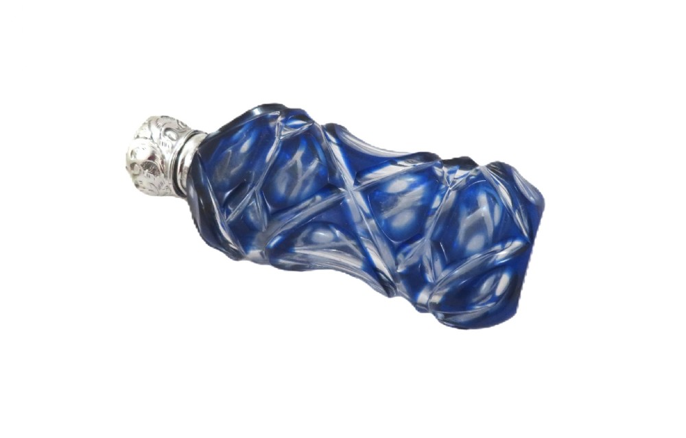 A Victorian cobalt blue overlay cut glass scent bottle featuring geometric cut patterns and an embossed silver cap. View II