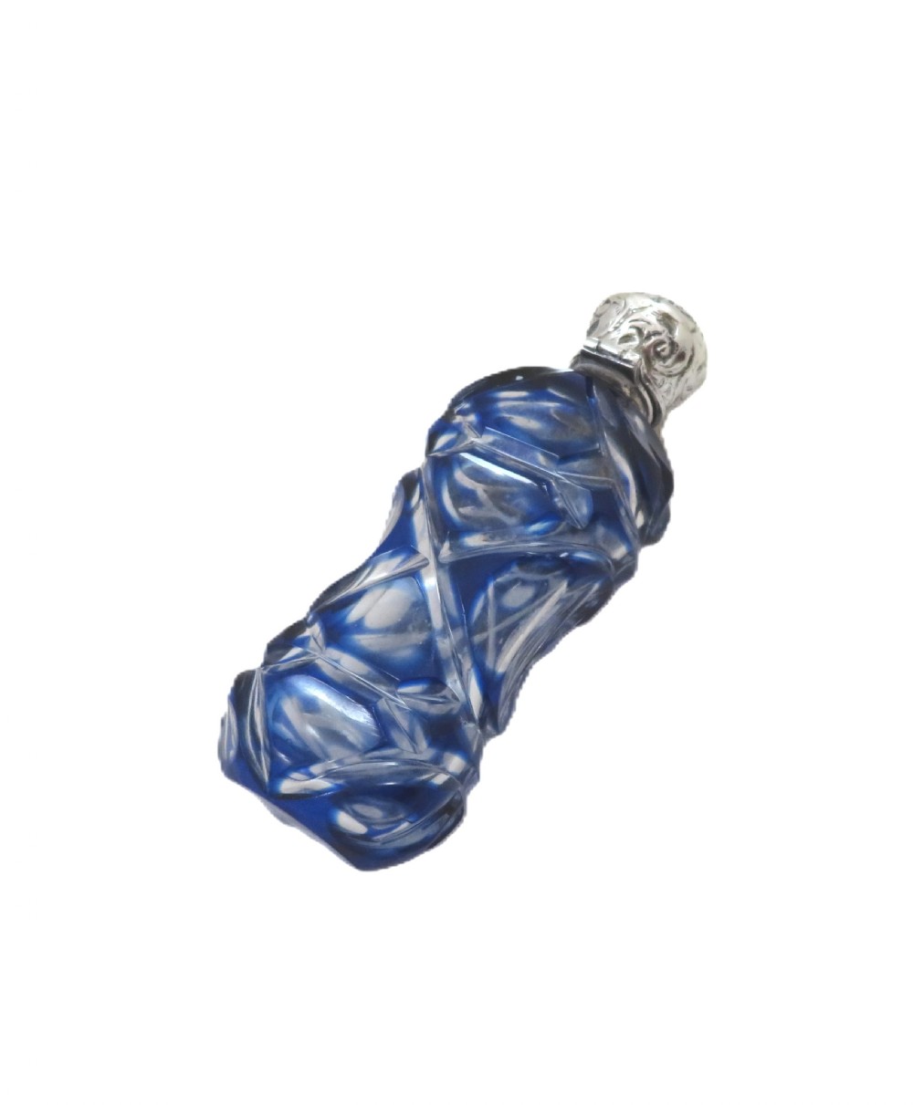A Victorian cobalt blue overlay cut glass scent bottle featuring geometric cut patterns and an embossed silver cap. View IV