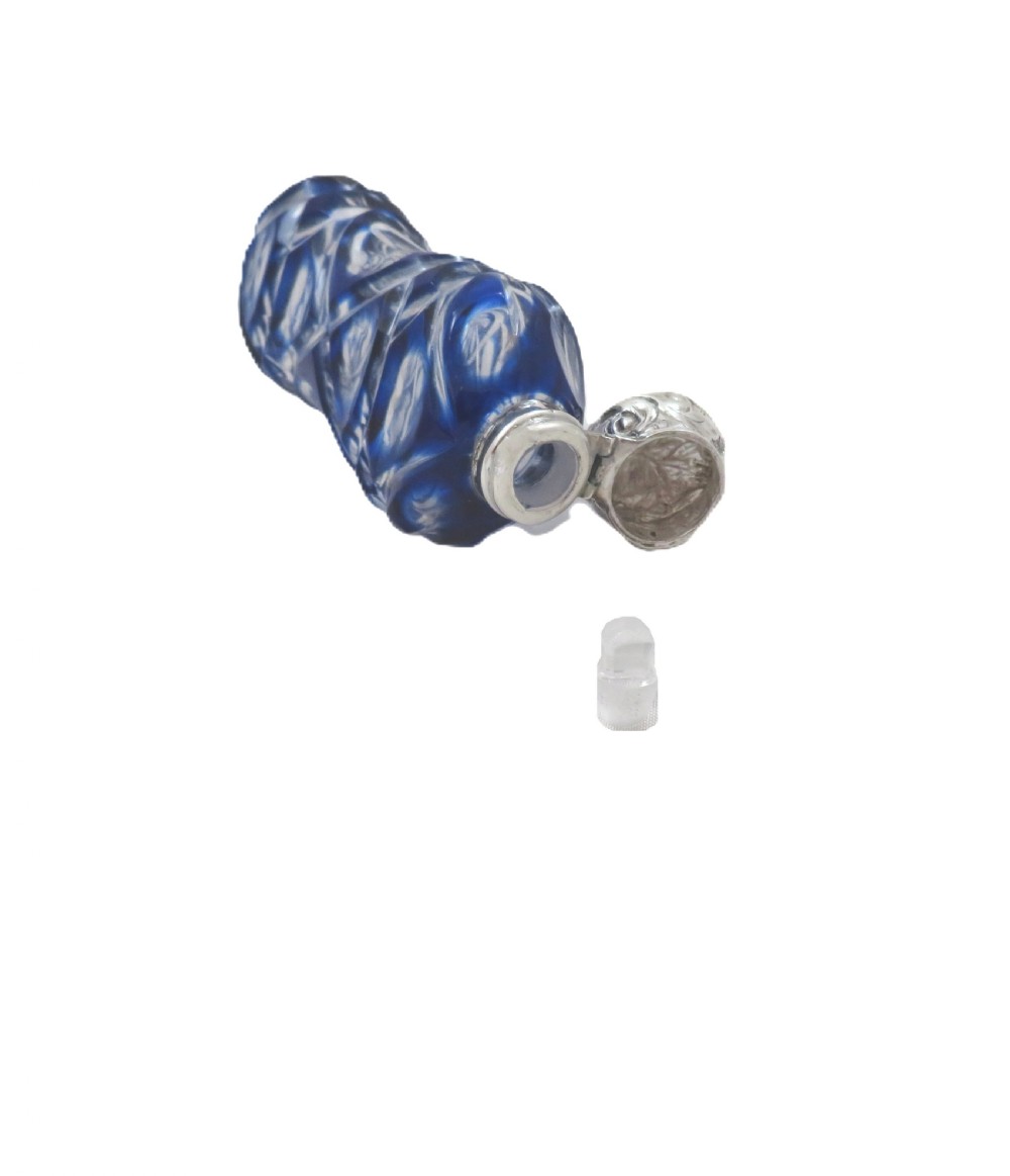 A Victorian cobalt blue overlay cut glass scent bottle featuring geometric cut patterns and an embossed silver cap. View VII