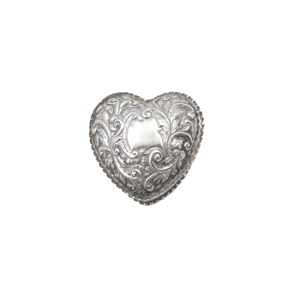 A heart-shaped sterling silver trinket box featuring detailed acanthus scroll repousse work around a smooth central cartouche.