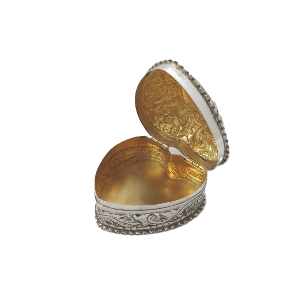 A heart-shaped sterling silver trinket box featuring detailed acanthus scroll repousse work around a smooth central cartouche. View III