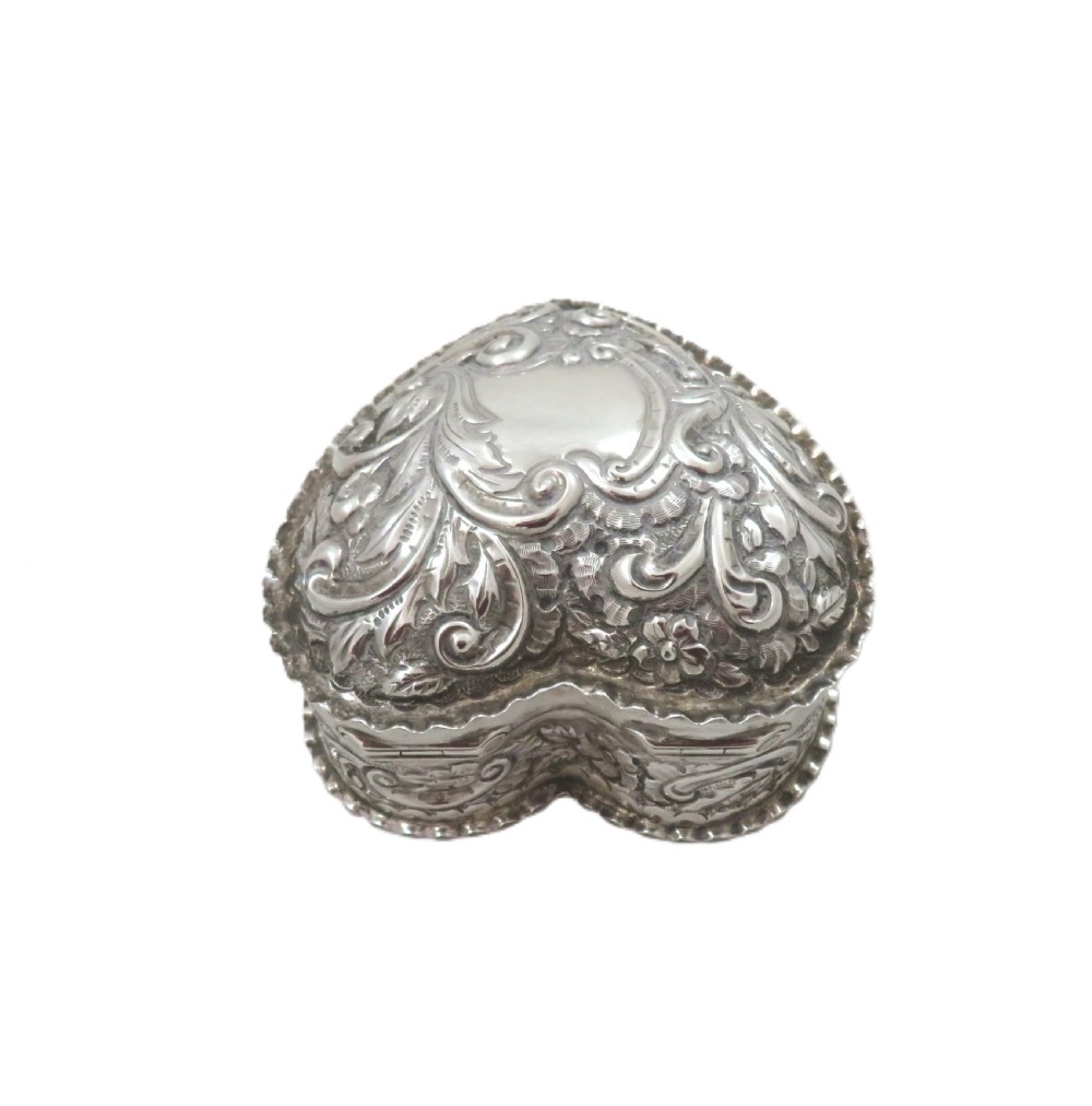 A heart-shaped sterling silver trinket box featuring detailed acanthus scroll repousse work around a smooth central cartouche. View VI