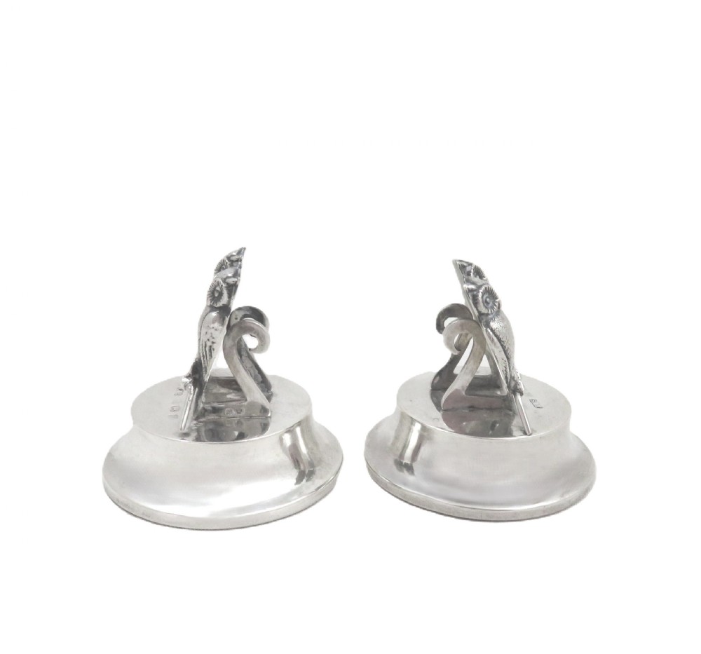 A pair of Edwardian sterling silver menu holders featuring double owl figures perched on round polished bases with visible silver hallmarks. View VII