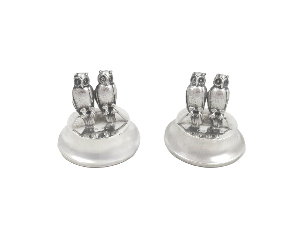 A pair of Edwardian sterling silver menu holders featuring double owl figures perched on round polished bases with visible silver hallmarks. View IX