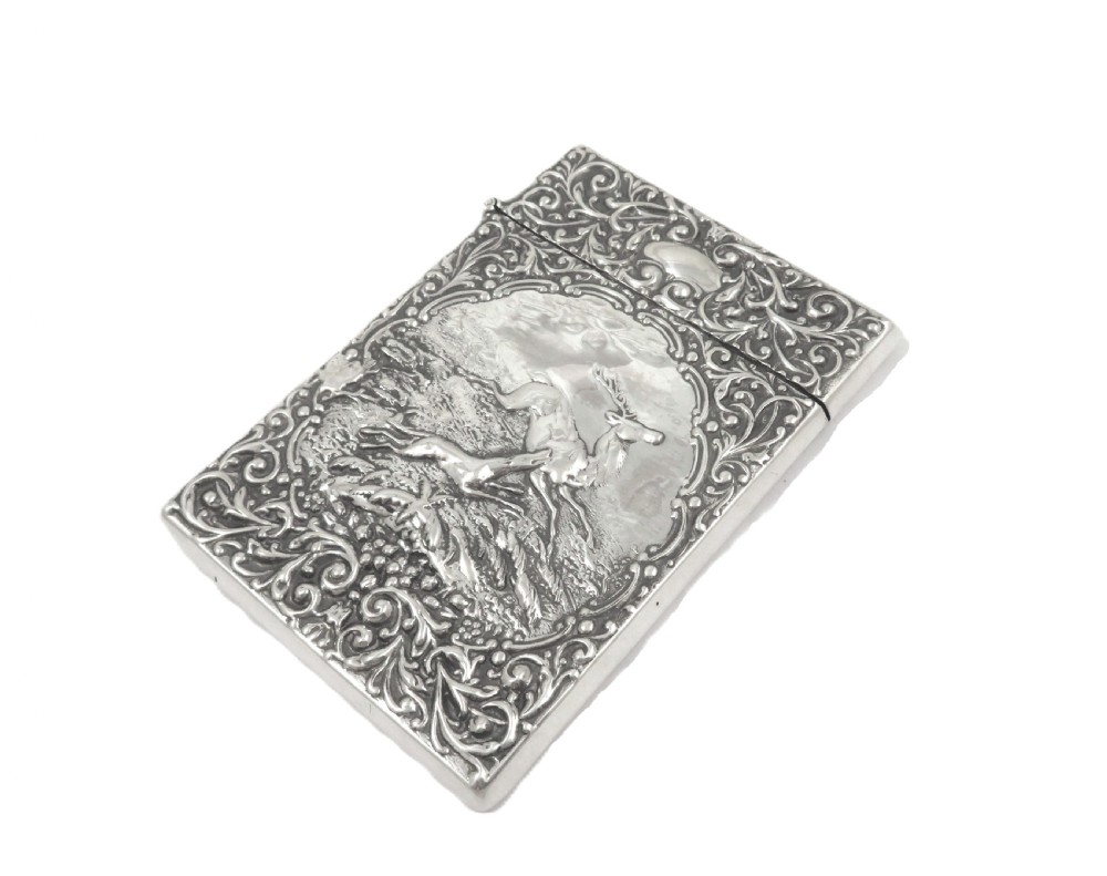 A rectangular Edwardian sterling silver card case decorated with repousse scrollwork and a central relief scene of a hound pursuing a stag. View V