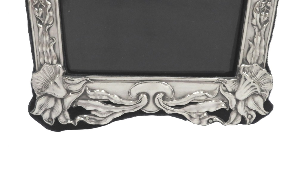 An embossed sterling silver Art Nouveau picture frame featuring stylised floral repousse motifs and a fabric-covered easel backing. View III