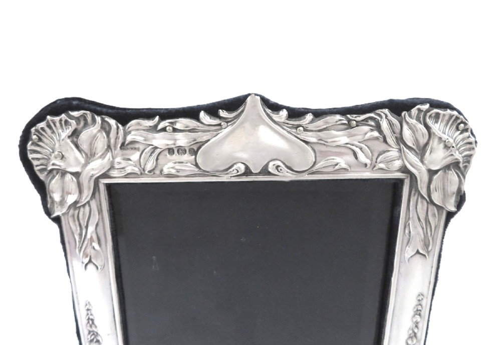 An embossed sterling silver Art Nouveau picture frame featuring stylised floral repousse motifs and a fabric-covered easel backing. View VI