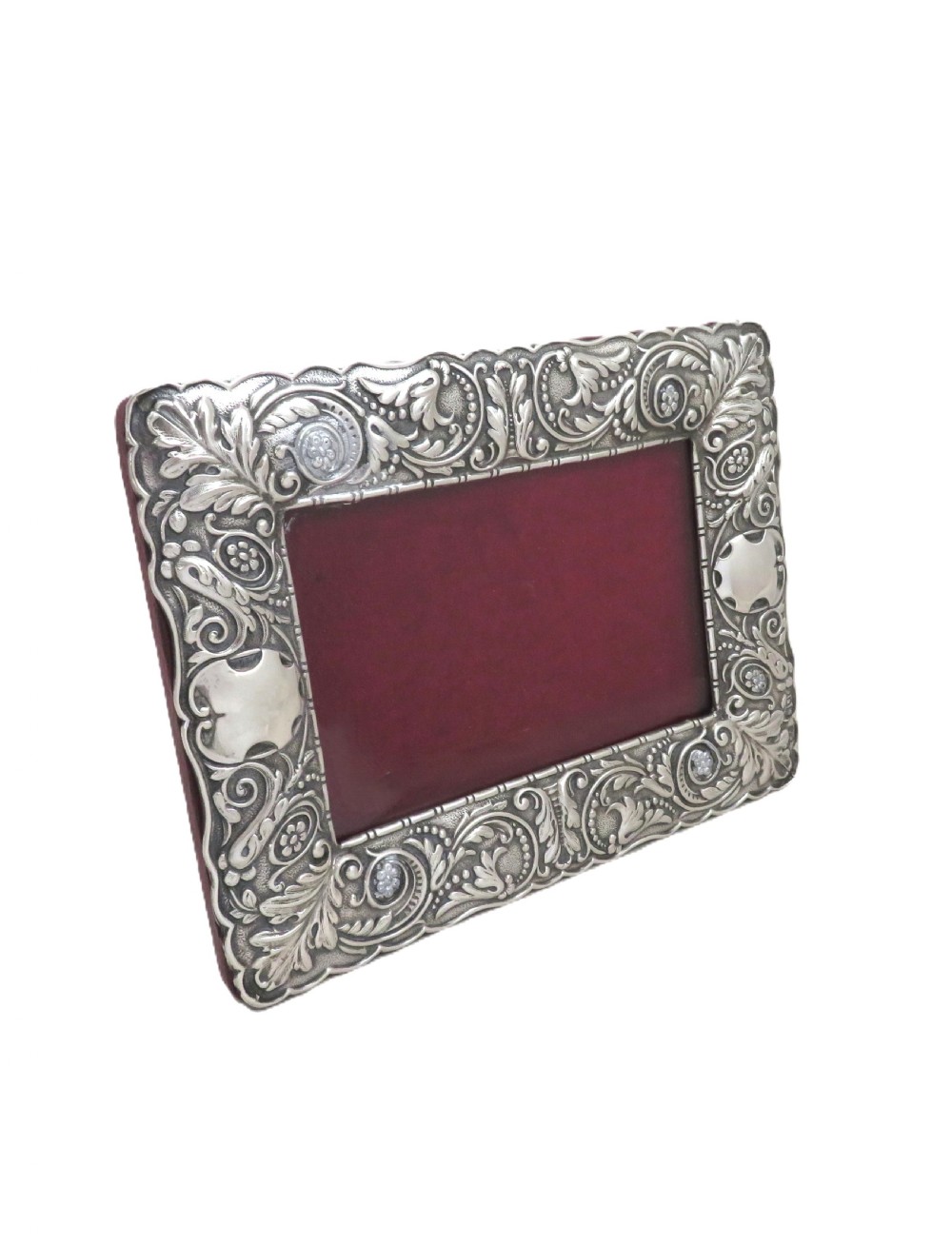 An Edwardian sterling silver landscape photo frame featuring repousse foliage motifs, a blank cartouche, and a dark velvet backing. View VI
