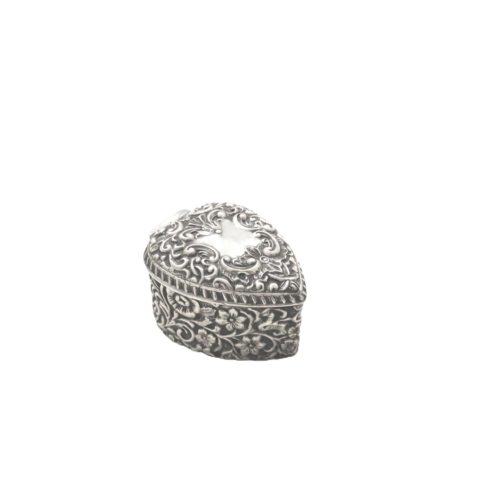 A heart-shaped sterling silver trinket box featuring intricate chased floral motifs and scrollwork.
