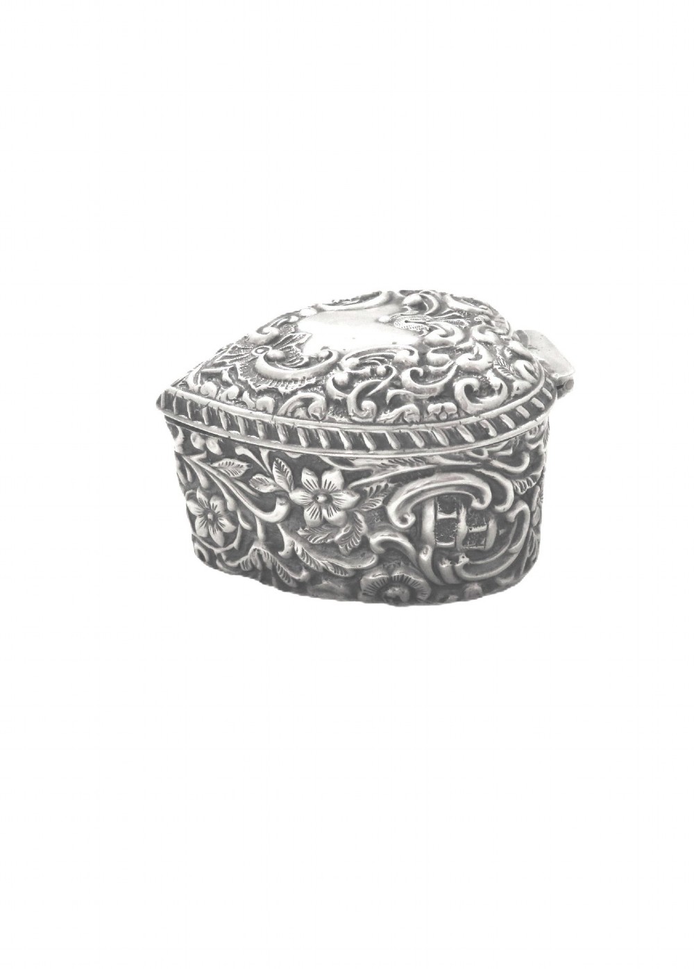 A heart-shaped sterling silver trinket box featuring intricate chased floral motifs and scrollwork. View III