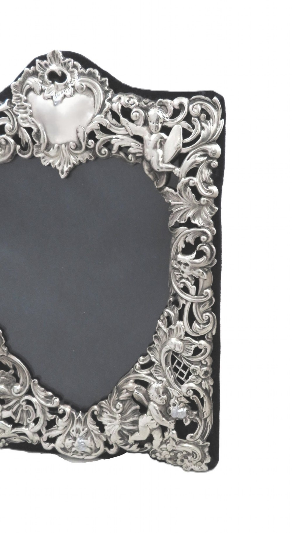 An antique Victorian sterling silver easel photo frame featuring a heart-shaped central opening surrounded by embossed cherubs, foliate scrolls, and a blank top cartouche. View III