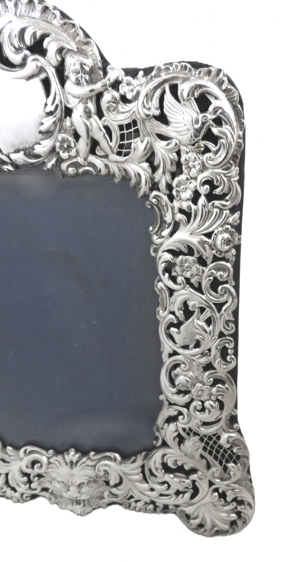An ornate late Victorian sterling silver photo frame featuring intricate pierced scrollwork, cherub figures, birds, and a central lion mask at the base. View III