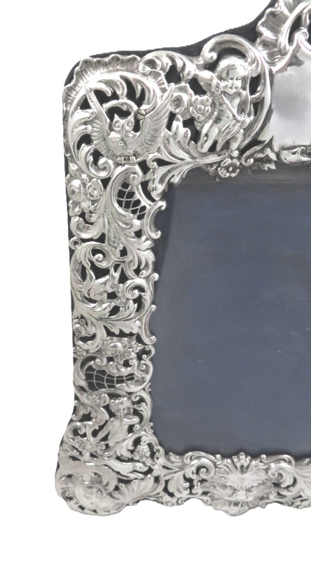 An ornate late Victorian sterling silver photo frame featuring intricate pierced scrollwork, cherub figures, birds, and a central lion mask at the base. View VI