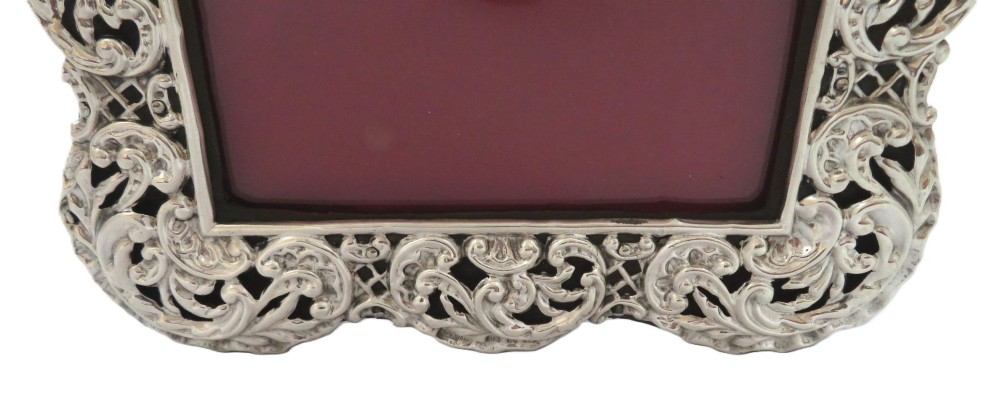 An antique Victorian sterling silver photo frame featuring intricate scrollwork, pierced openwork detail, a rectangular aperture, and a maroon backing. View VIII