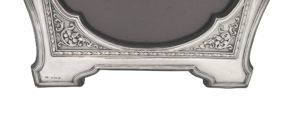 An ornate Edwardian sterling silver portrait photo frame featuring a ribbon crest and shaped border, resting on an easel back. View III