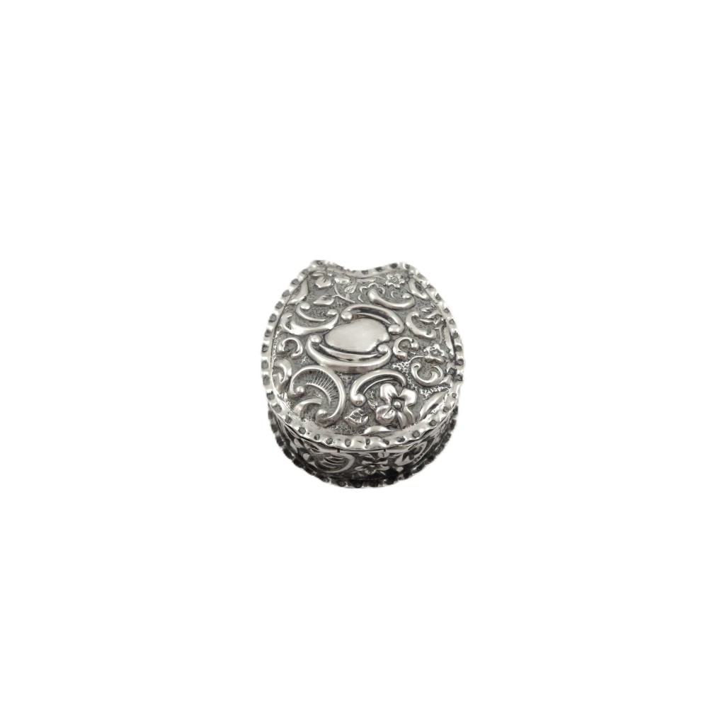A small horseshoe-shaped sterling silver trinket box featuring embossed floral scrollwork and a central vacant cartouche.
