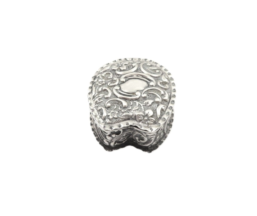 A small horseshoe-shaped sterling silver trinket box featuring embossed floral scrollwork and a central vacant cartouche. View VI