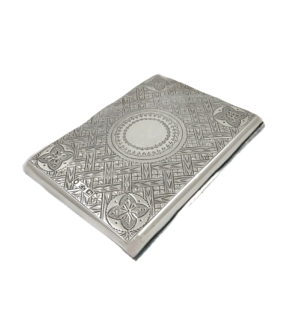 An antique Victorian sterling silver card case featuring geometric engine turning, floral engraving, and British silver hallmarks. View V