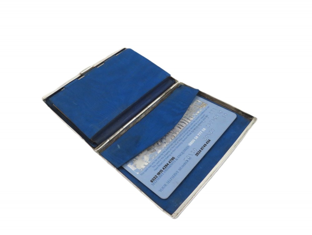 An antique Victorian sterling silver card case featuring geometric engine turning, floral engraving, and British silver hallmarks. View X