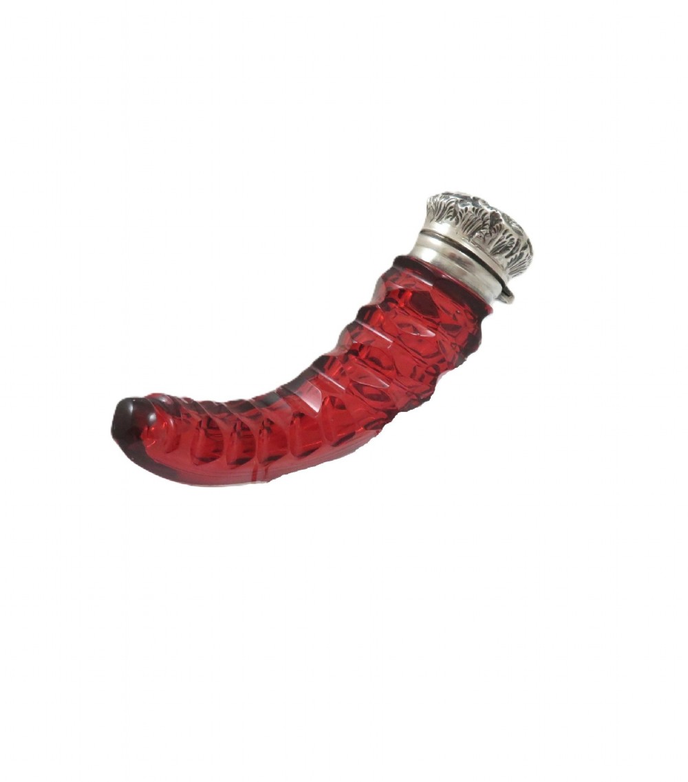 A horn-shaped red cranberry glass scent bottle featuring faceted cut glass detailing and an embossed sterling silver cap.