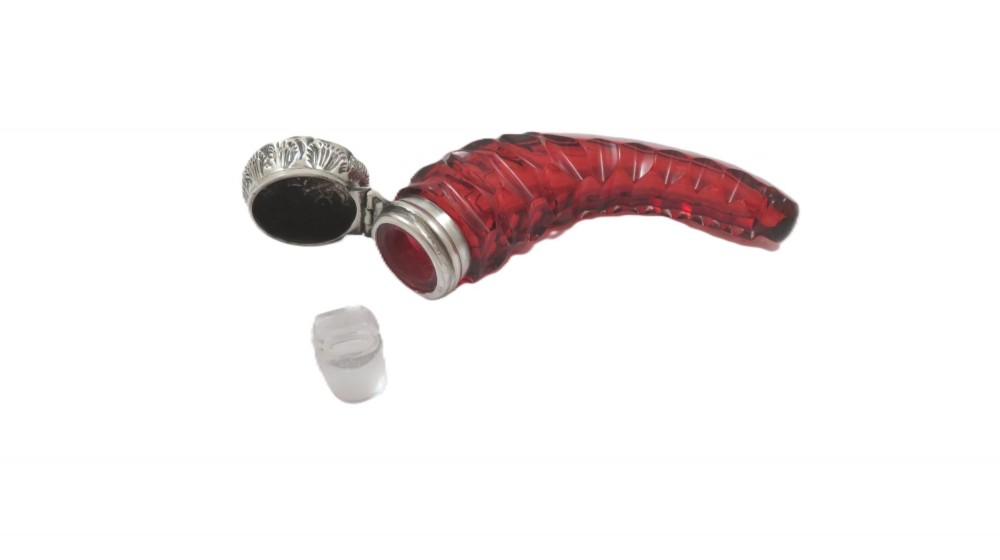 A horn-shaped red cranberry glass scent bottle featuring faceted cut glass detailing and an embossed sterling silver cap. View II