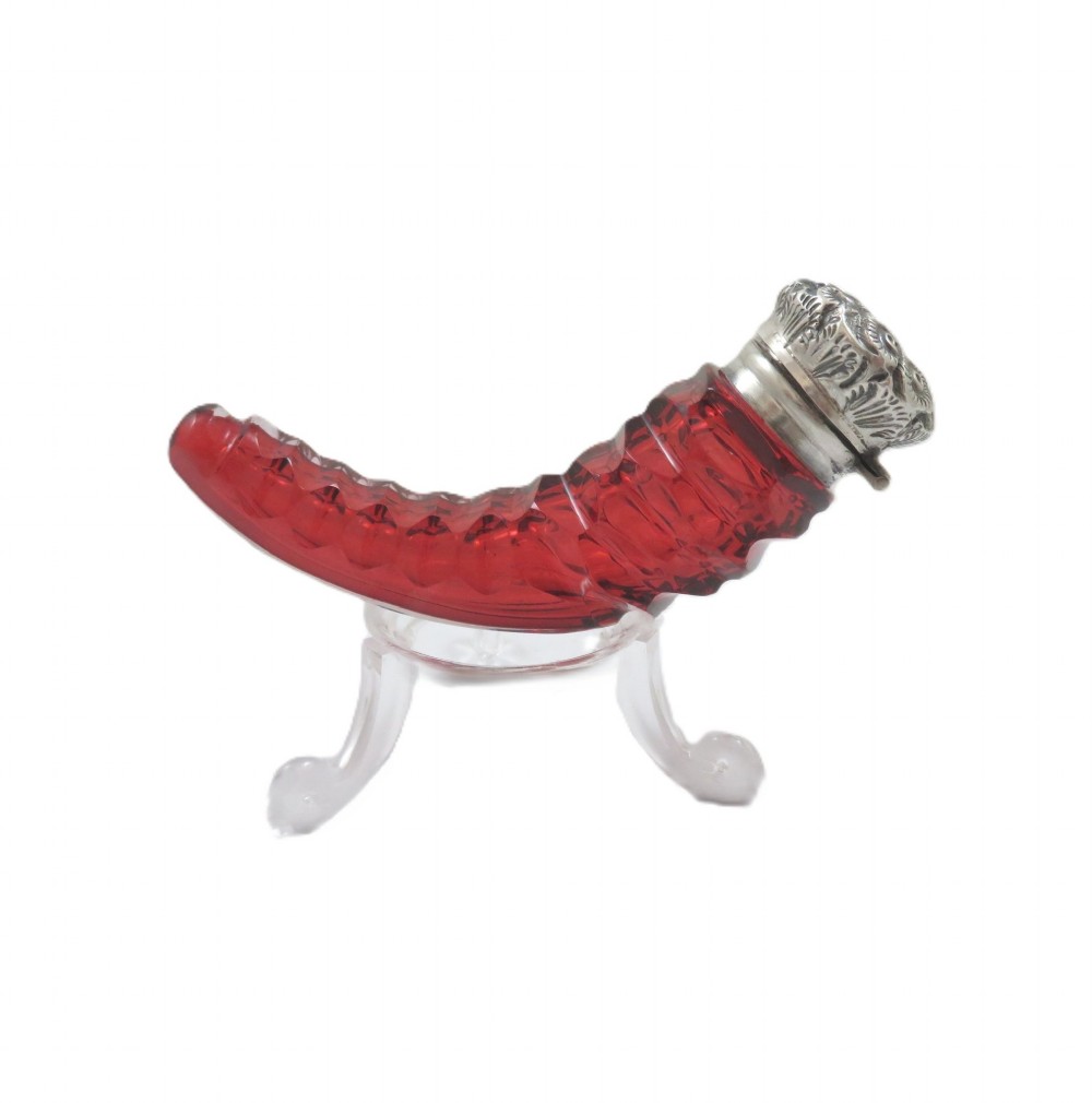 A horn-shaped red cranberry glass scent bottle featuring faceted cut glass detailing and an embossed sterling silver cap. View IV
