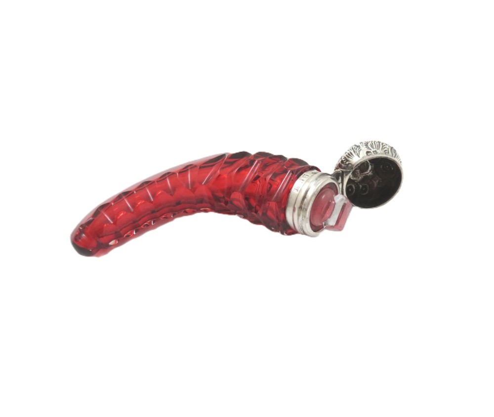 A horn-shaped red cranberry glass scent bottle featuring faceted cut glass detailing and an embossed sterling silver cap. View V