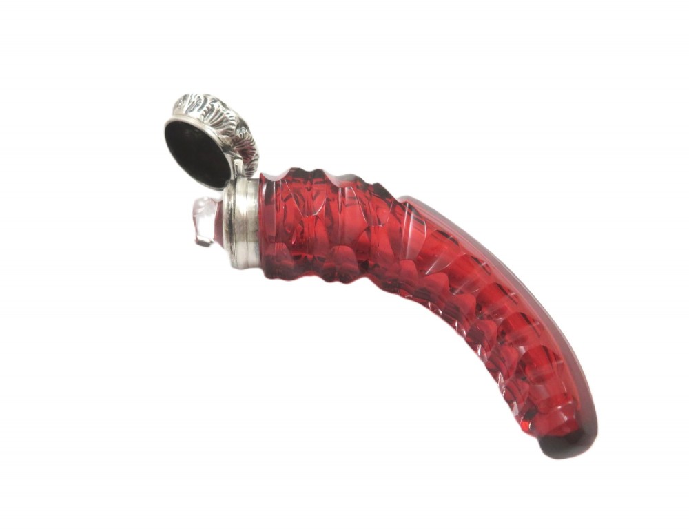 A horn-shaped red cranberry glass scent bottle featuring faceted cut glass detailing and an embossed sterling silver cap. View VI