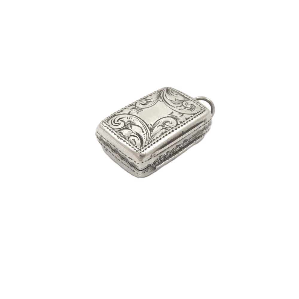 An antique rectangular sterling silver vinaigrette featuring foliate scroll engraving and an attached suspension loop.