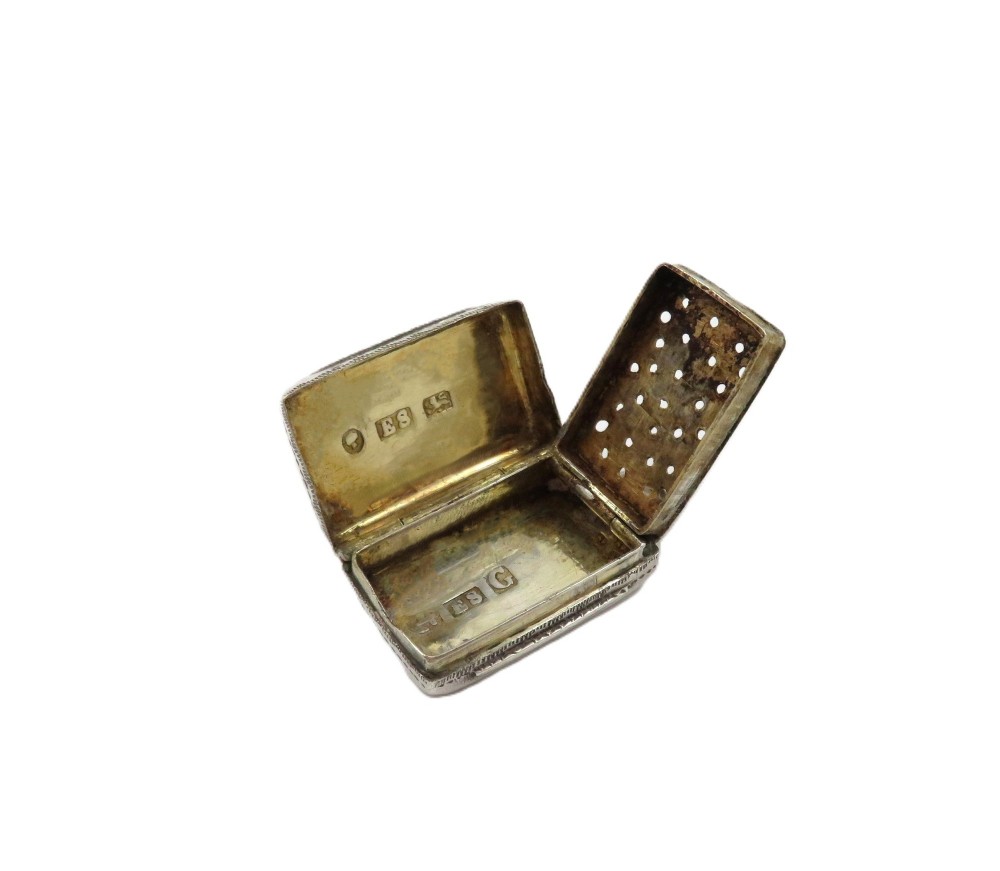 An antique rectangular sterling silver vinaigrette featuring foliate scroll engraving and an attached suspension loop. View V