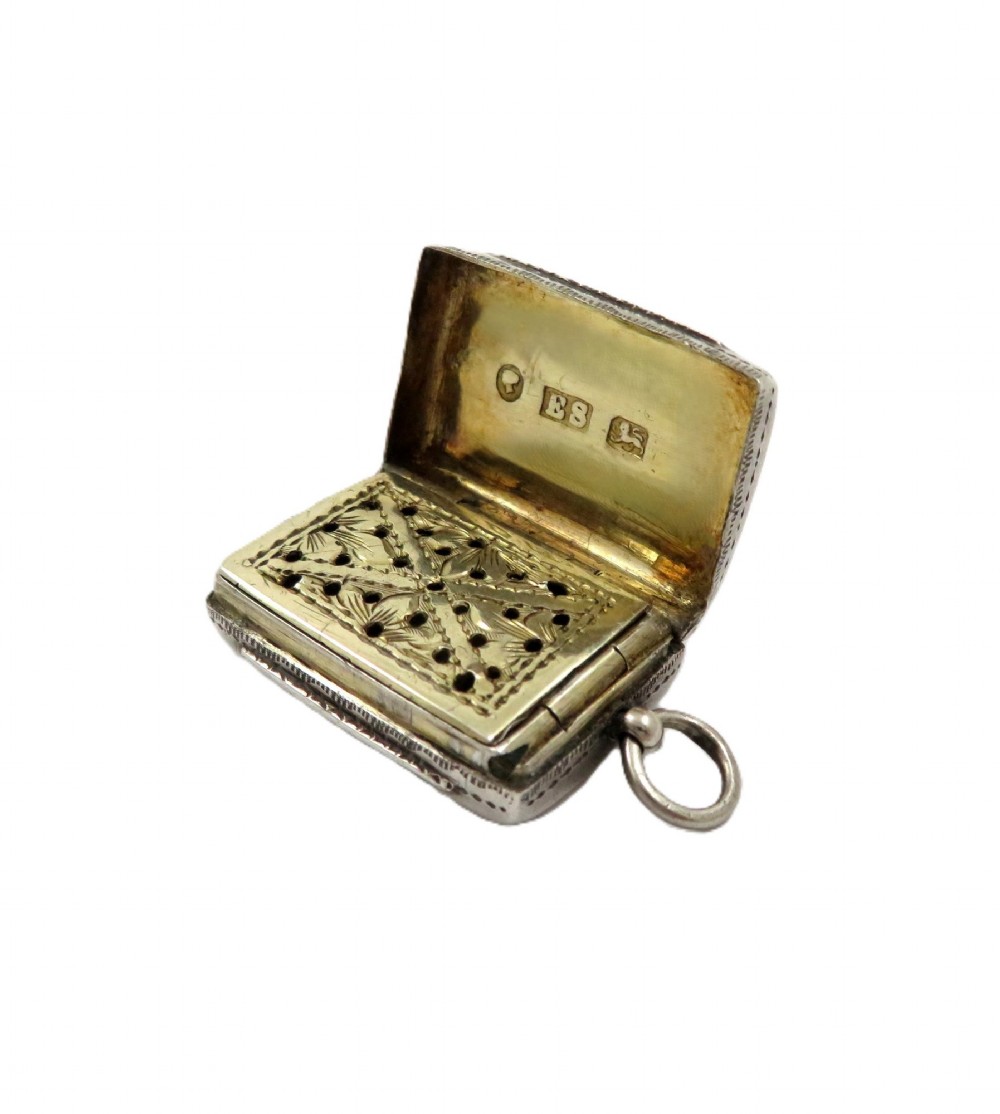 An antique rectangular sterling silver vinaigrette featuring foliate scroll engraving and an attached suspension loop. View VII