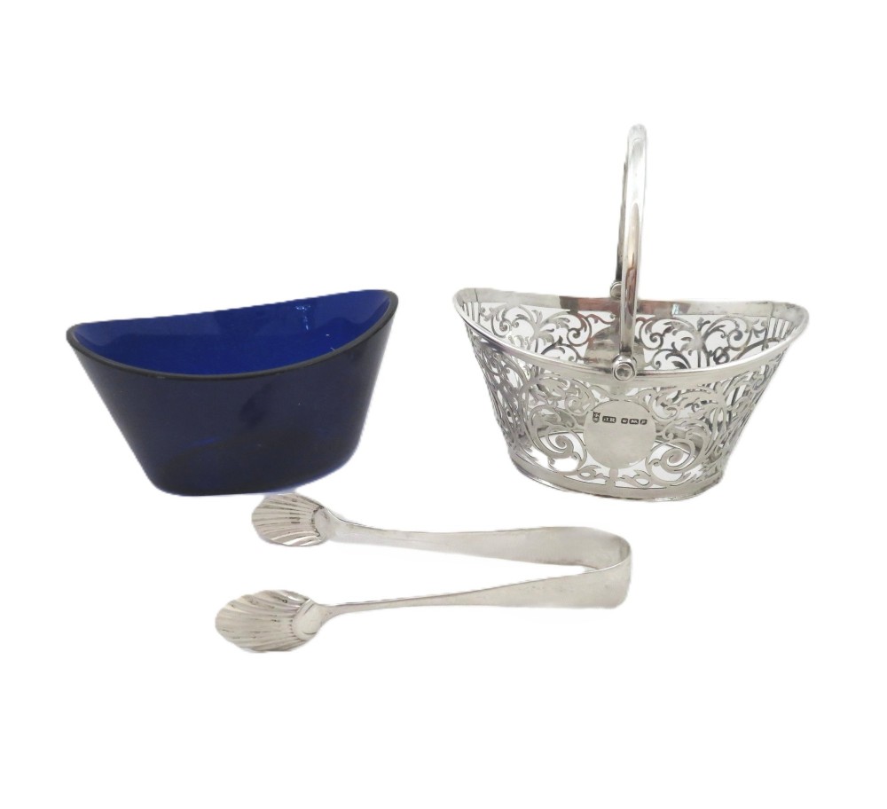 An Edwardian hallmarked sterling silver pierced sugar basket with a cobalt blue glass liner and matching silver sugar tongs in an open presentation case. View III