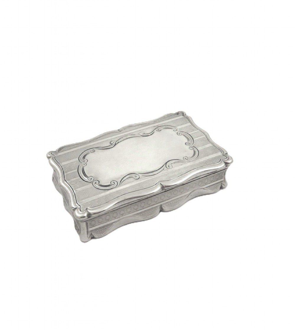 A rectangular Victorian sterling silver snuff box featuring scalloped edges, engine-turned linear engraving, and an unengraved scrollwork cartouche on the lid. View V