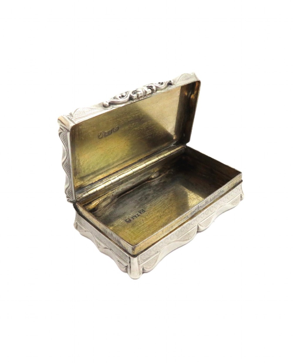 A rectangular Victorian sterling silver snuff box featuring scalloped edges, engine-turned linear engraving, and an unengraved scrollwork cartouche on the lid. View VI
