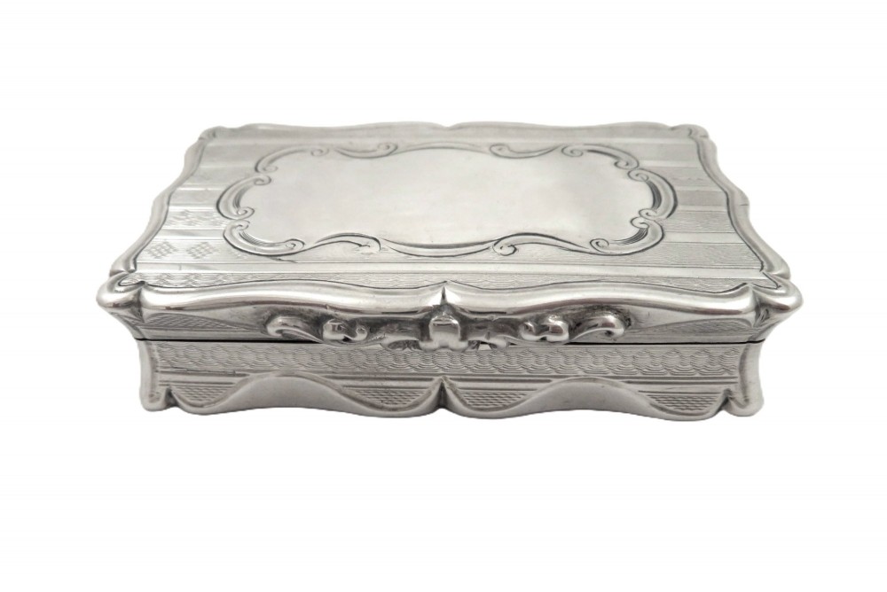 A rectangular Victorian sterling silver snuff box featuring scalloped edges, engine-turned linear engraving, and an unengraved scrollwork cartouche on the lid. View VIII
