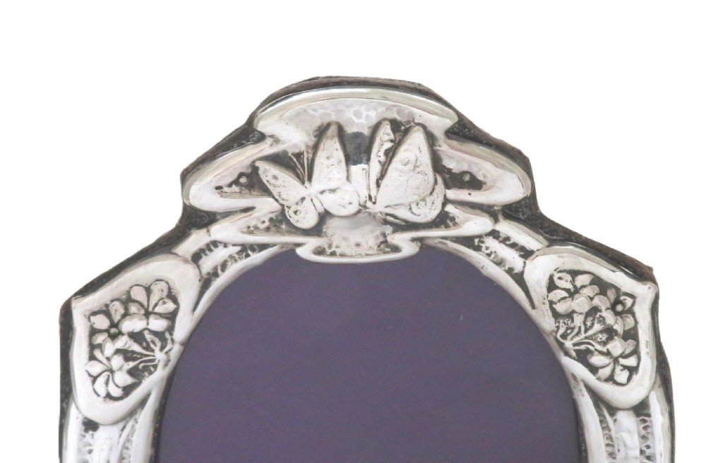 An Art Nouveau sterling silver photo frame featuring an oval aperture surrounded by embossed butterflies and floral motifs. View V