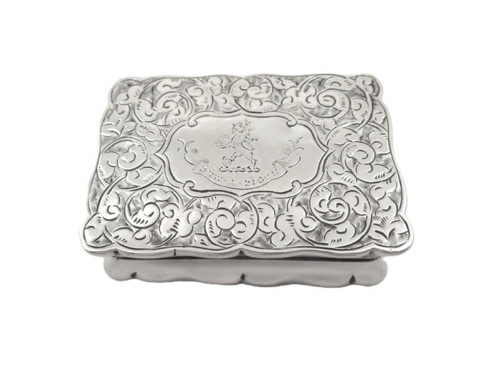 An antique Victorian rectangular sterling silver box featuring chased floral scrollwork and a central engraved crest on the lid. View V