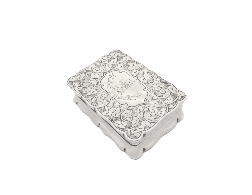 An antique Victorian rectangular sterling silver box featuring chased floral scrollwork and a central engraved crest on the lid. View VII