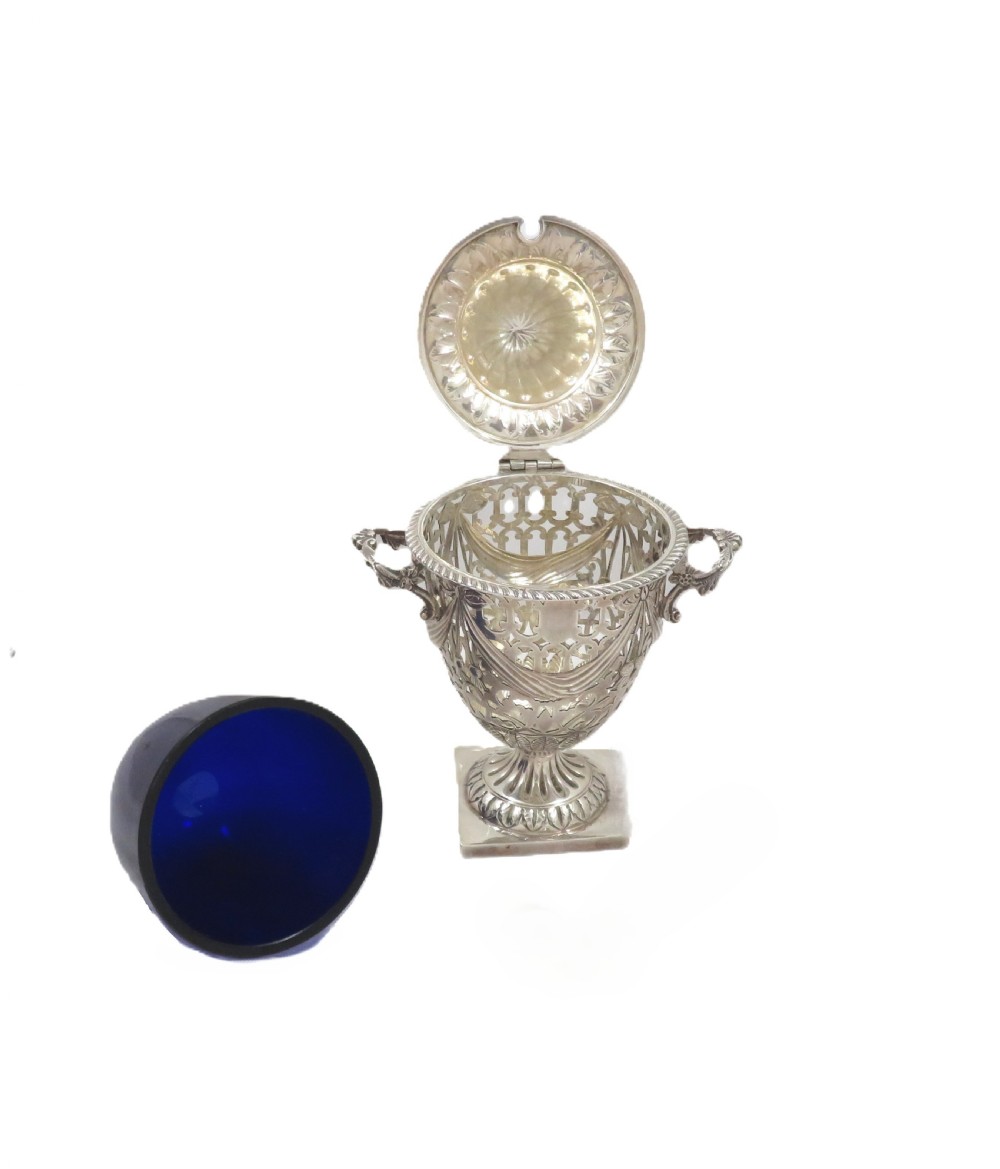 An Edwardian sterling silver sugar urn featuring pierced garland decoration, a cobalt blue glass liner, a fluted lid, and a silver spoon. View III