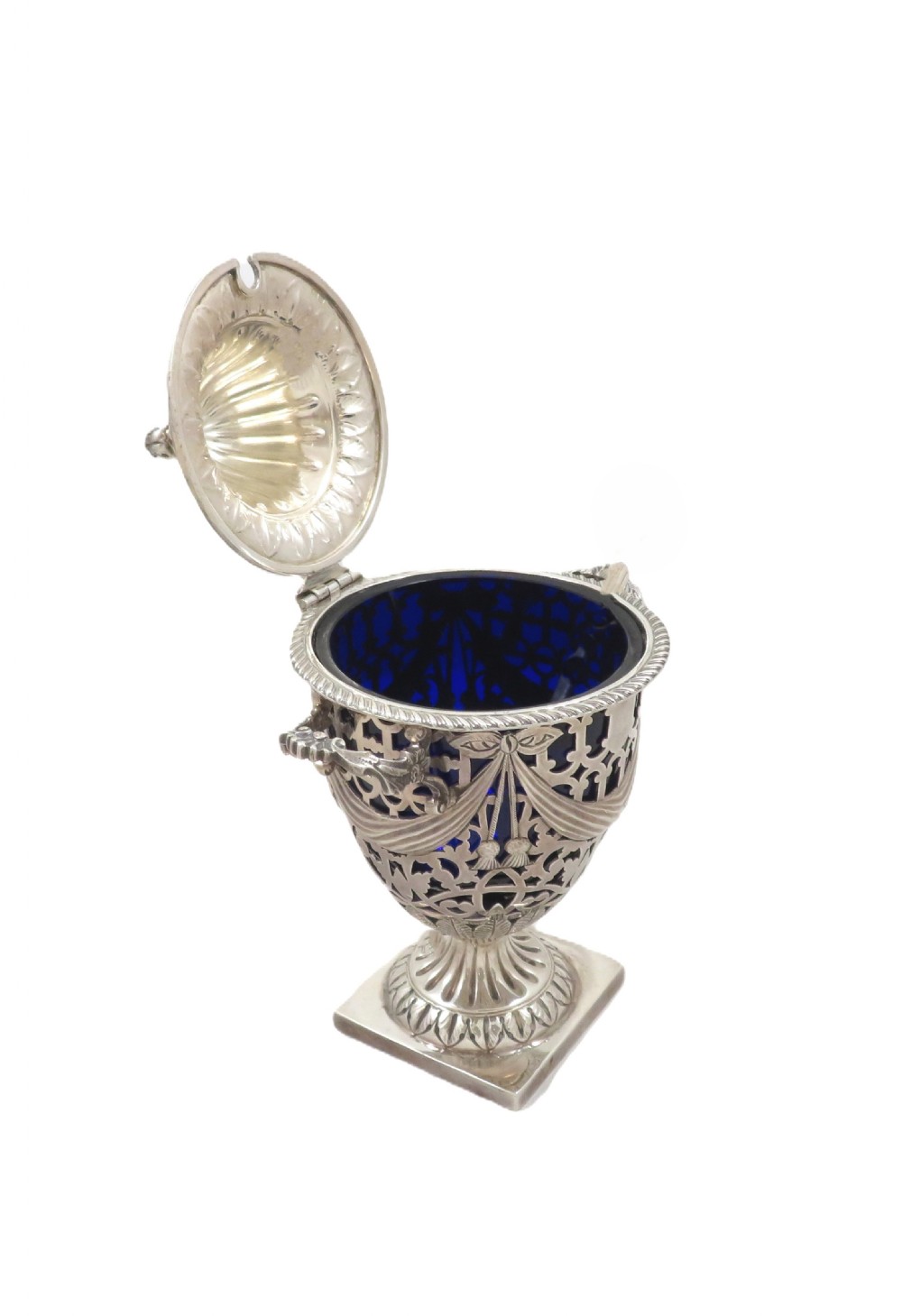 An Edwardian sterling silver sugar urn featuring pierced garland decoration, a cobalt blue glass liner, a fluted lid, and a silver spoon. View V