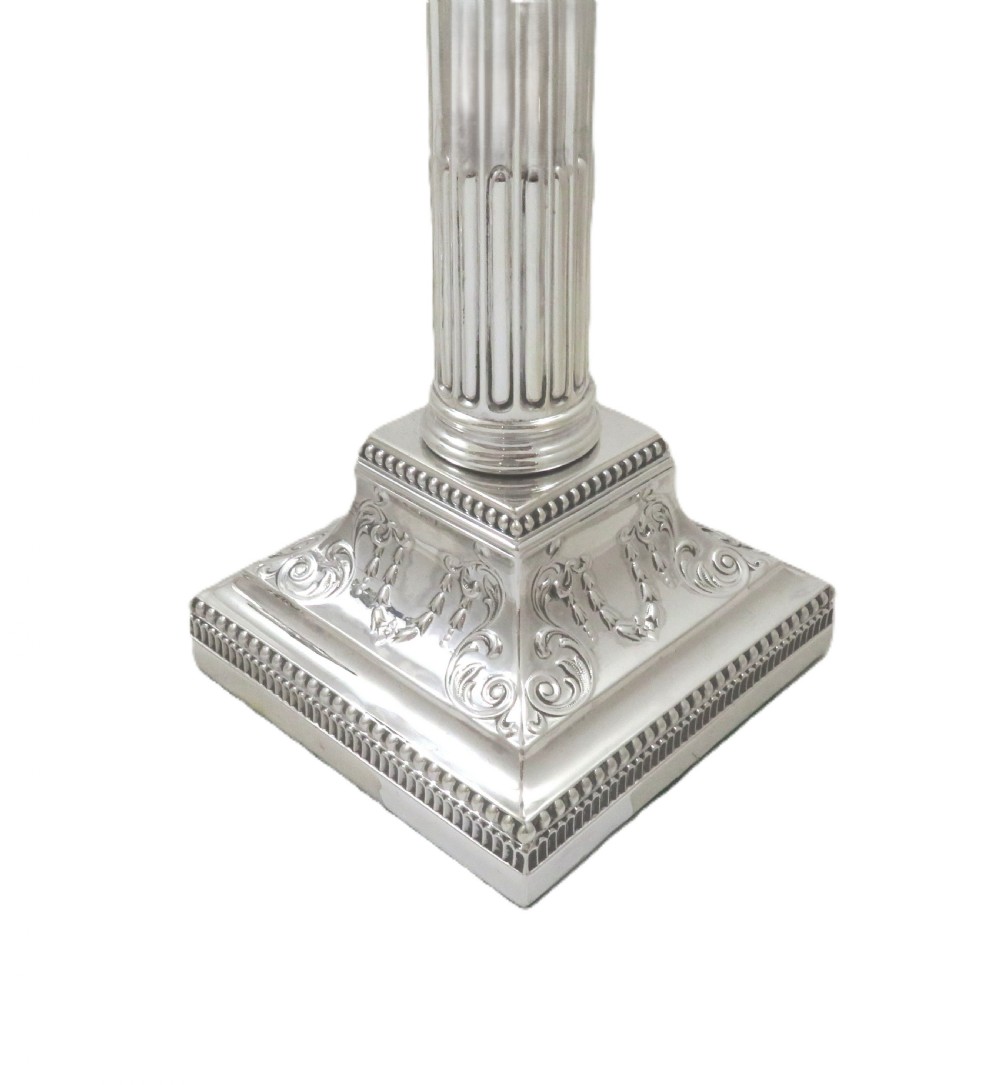 A pair of antique sterling silver candlesticks featuring fluted Corinthian columns on square decorated stepped bases. View III