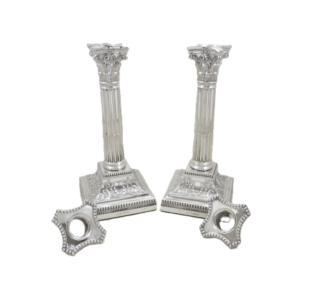 A pair of antique sterling silver candlesticks featuring fluted Corinthian columns on square decorated stepped bases. View IV