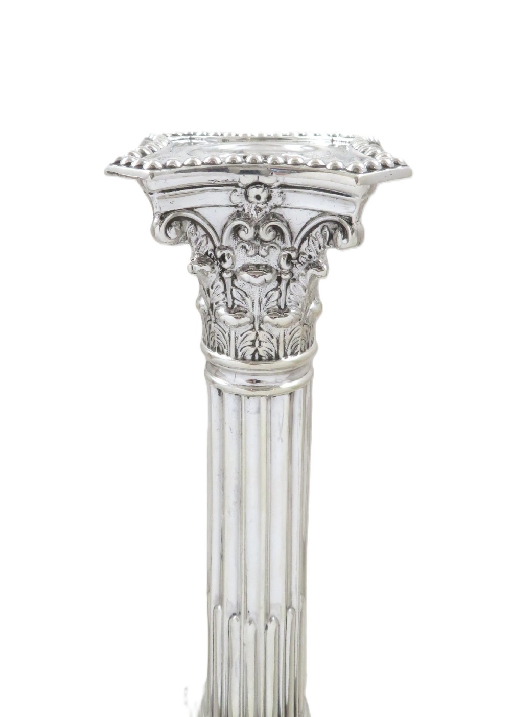 A pair of antique sterling silver candlesticks featuring fluted Corinthian columns on square decorated stepped bases. View V